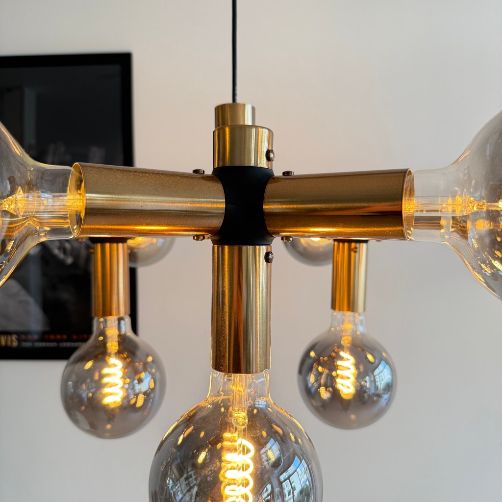 Close-up of a modern pendant lamp featuring multiple transparent light bulbs with a brass structure.