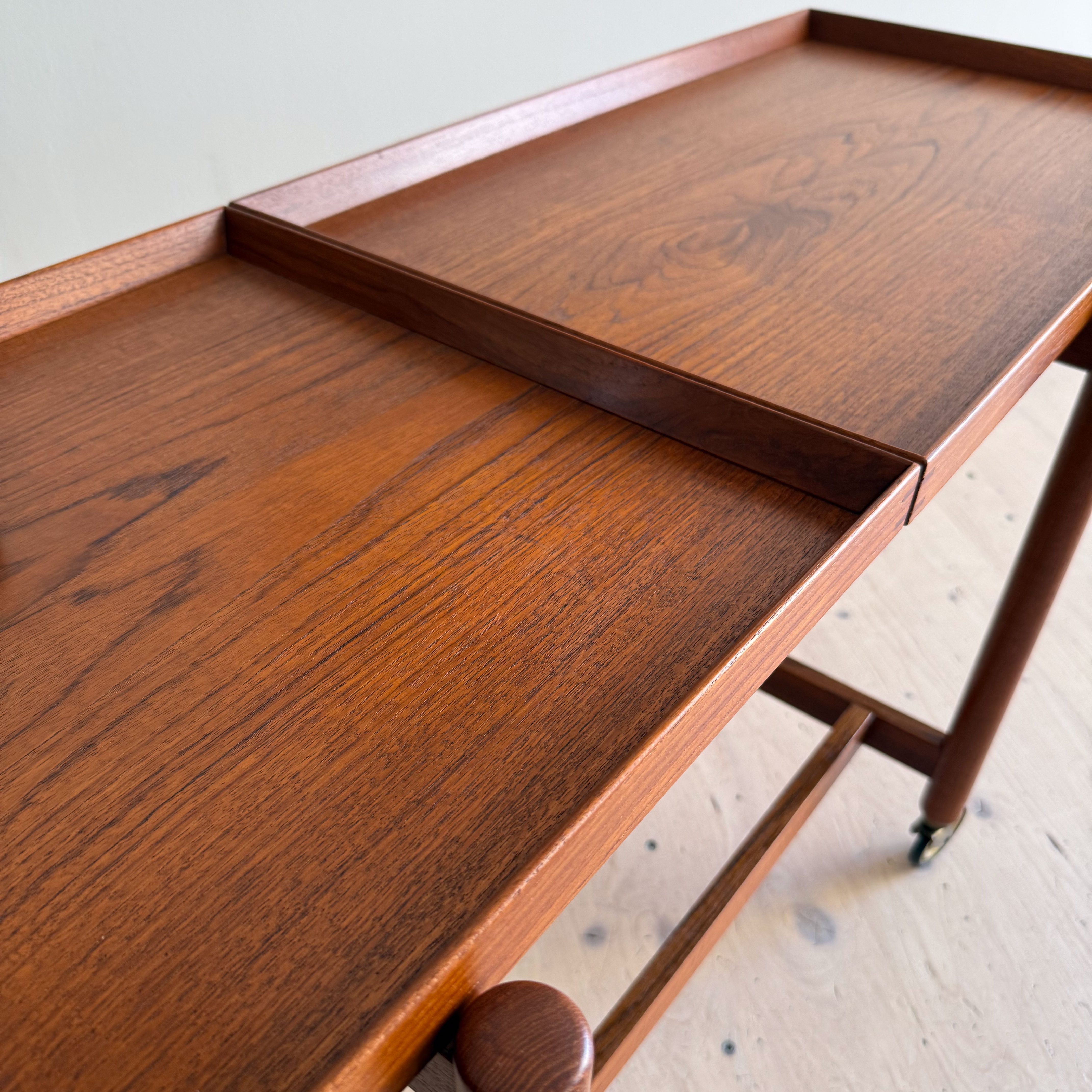 Close-up of a wooden serving cart with a smooth, polished surface, showcasing a rich wood grain and a small divider.
