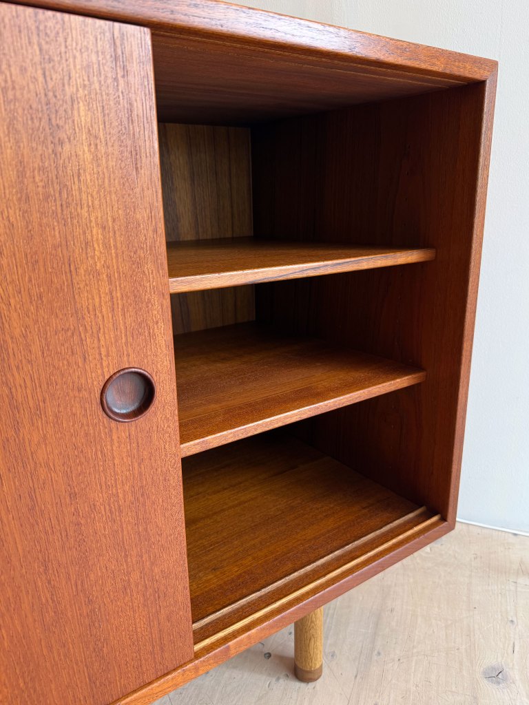 Close-up view of a wooden cabinet showcasing its open interior with two shelves and a round handle.