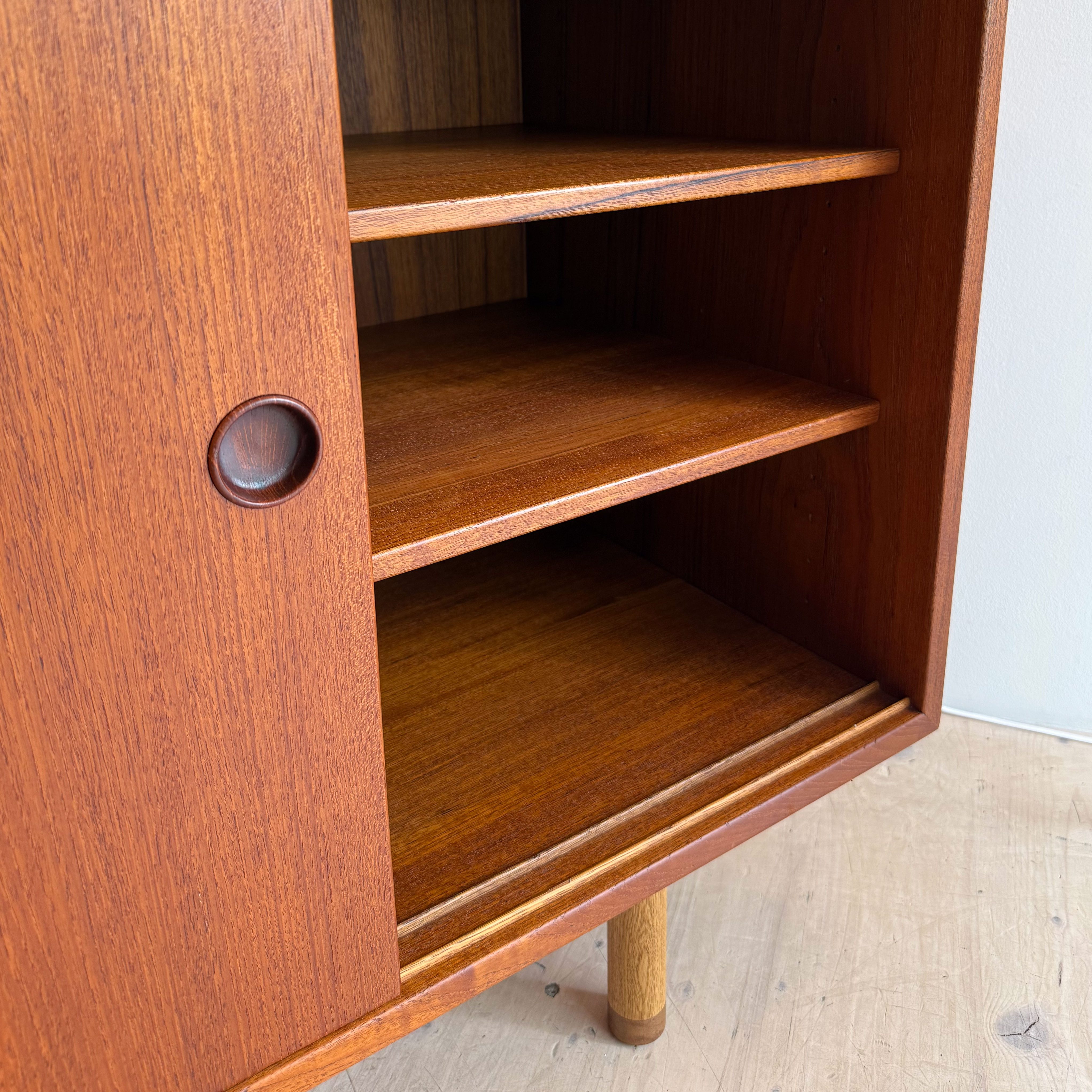Close-up of a wooden cabinet showing the inside shelves and a circular handle on the left door.