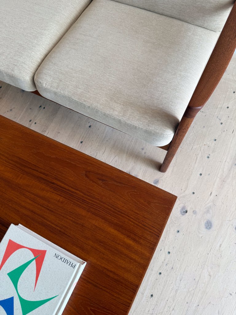 Close-up of a light-colored sofa and a wooden coffee table with a book on it, showcasing a minimalist interior design.