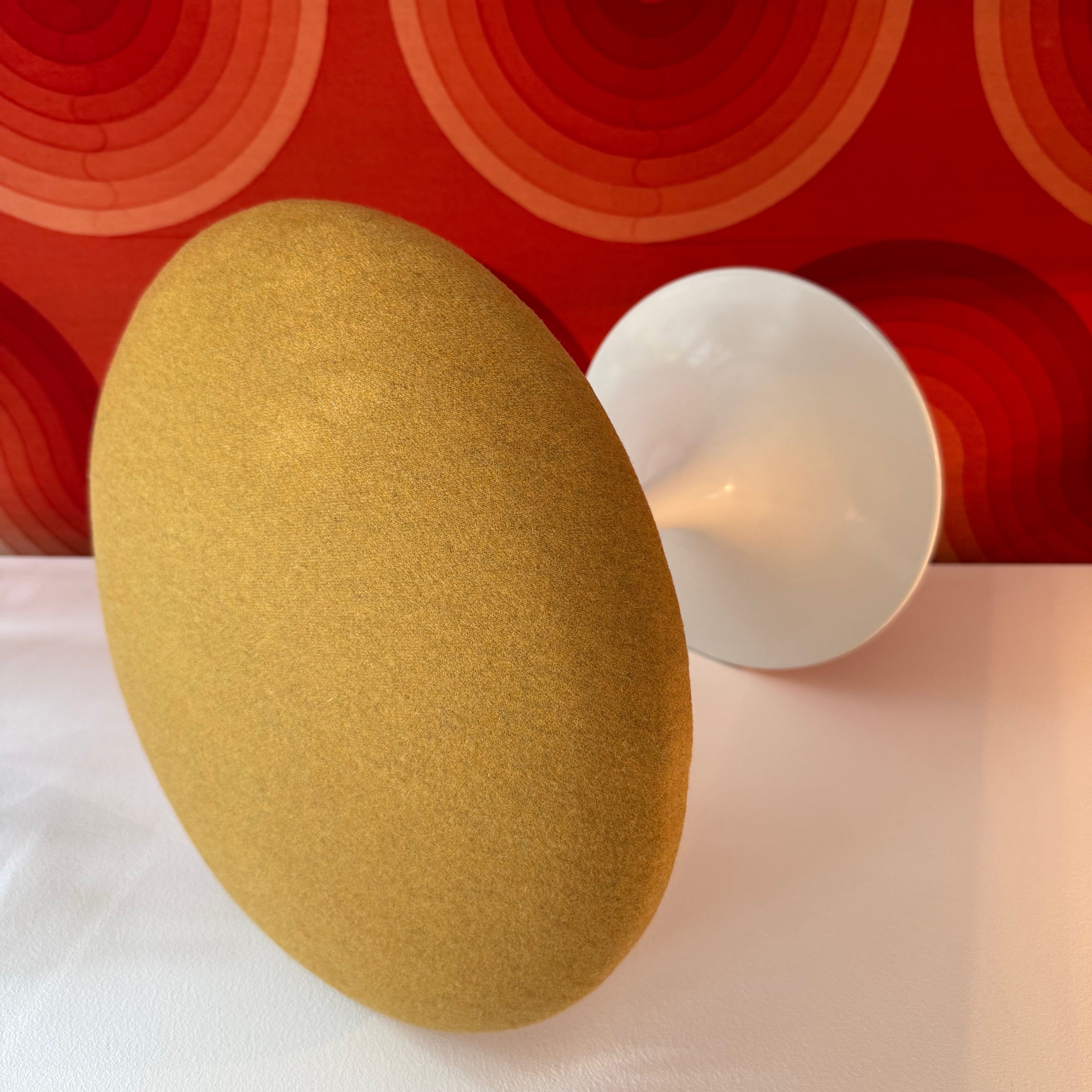 A round yellow object with a soft surface stands against a vibrant red background featuring wavy patterns.