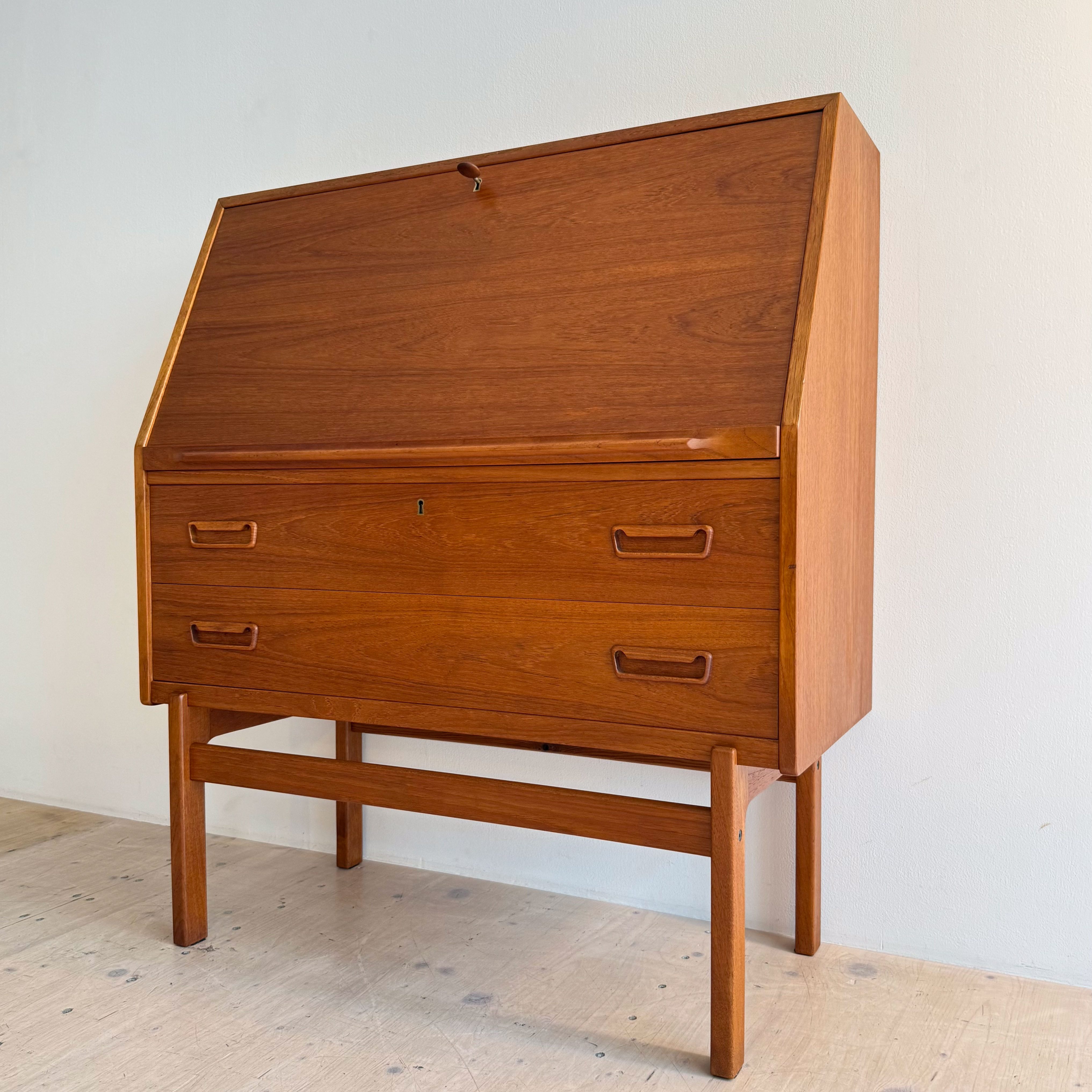A wooden writing desk with a slanted top and two drawers, showcasing minimalist design and craftsmanship.