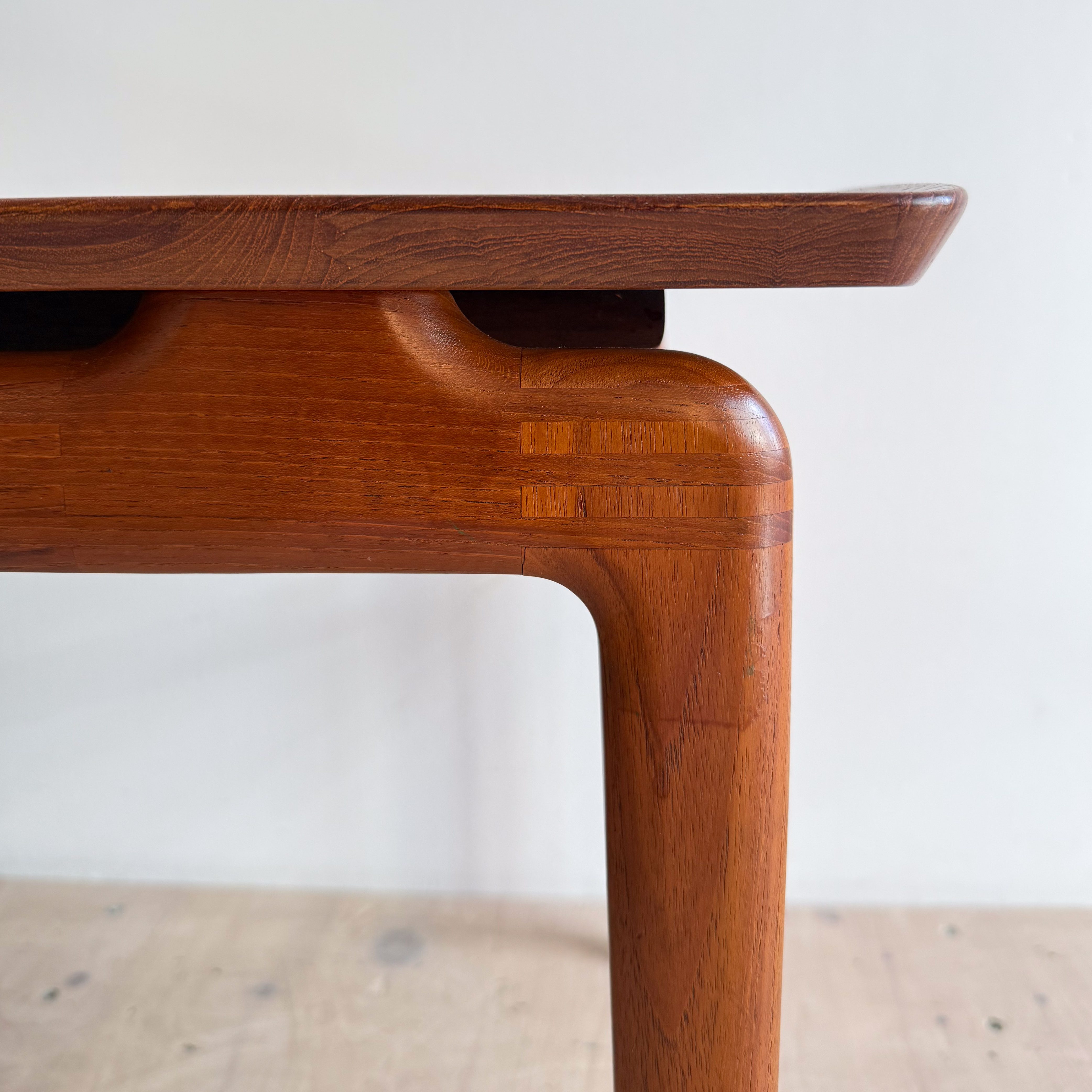 Side view of a wooden table showcasing the craftsmanship and detailing of the legs and top.