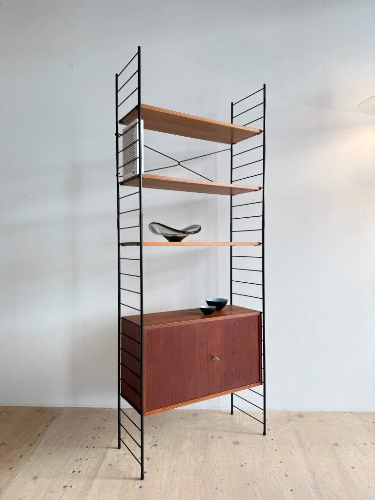 A modern wooden shelf unit with metal frame, featuring three open shelves and a lower cabinet, styled with decorative bowls on top.
