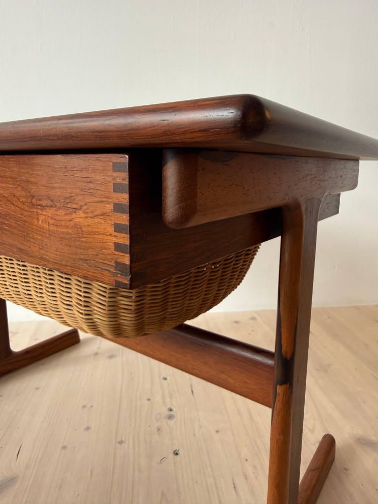 Close-up view of a wooden table with a woven wicker basket underneath, showcasing the craftsmanship and design details.