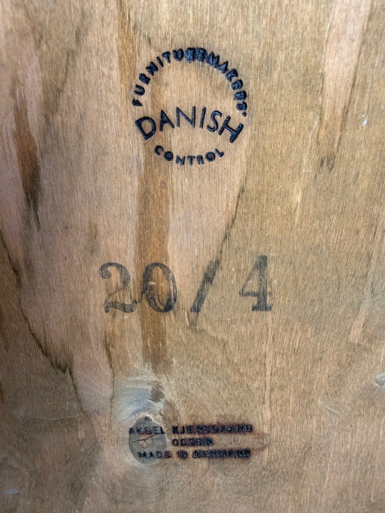 Close-up image of a wooden surface displaying a Danish control stamp, the number 20/4, and the name 'Axel Kjergaard,' indicating the piece was made in Denmark.