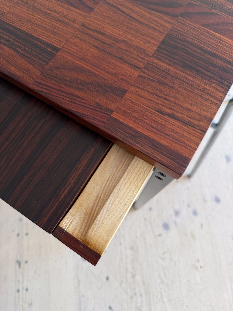 Close-up view of a wooden table with a rich, dark finish, showing an open drawer with a light wood interior.