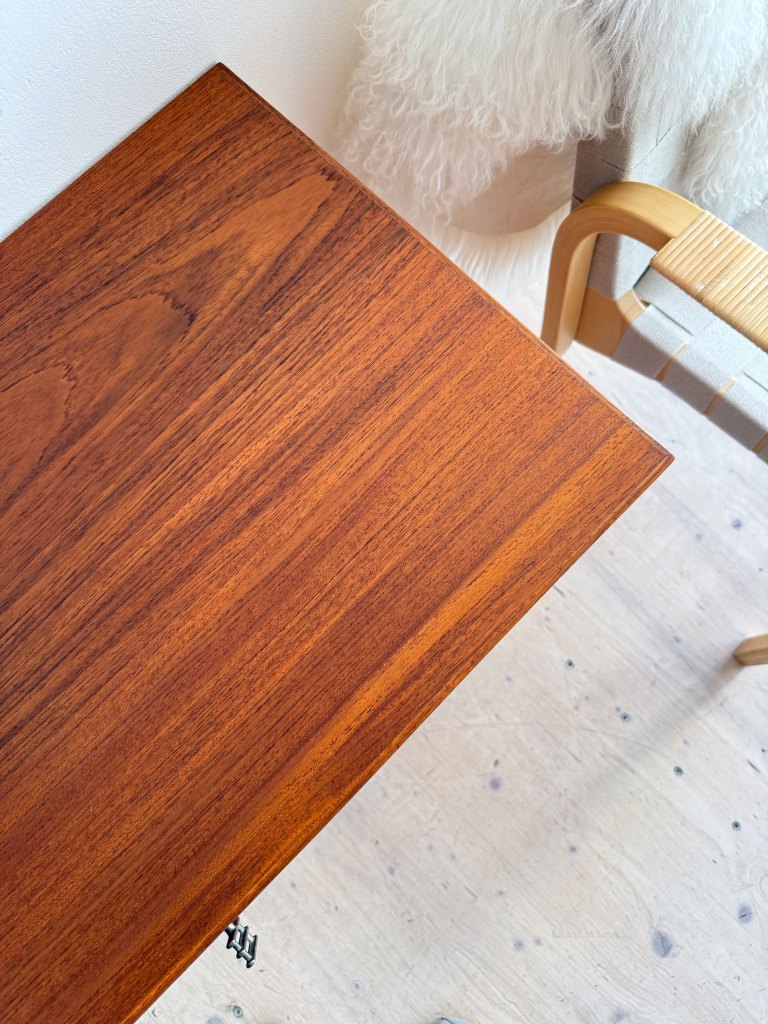 Top view of a polished wooden table with a rich, dark brown finish, showcasing its grain pattern, beside a beige and light-colored chair.