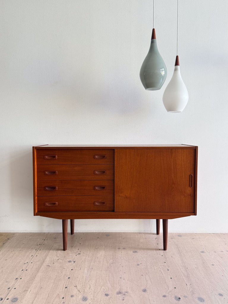 Mid-century modern wooden cabinet with five drawers and a sliding door, accompanied by two decorative hanging lamps.