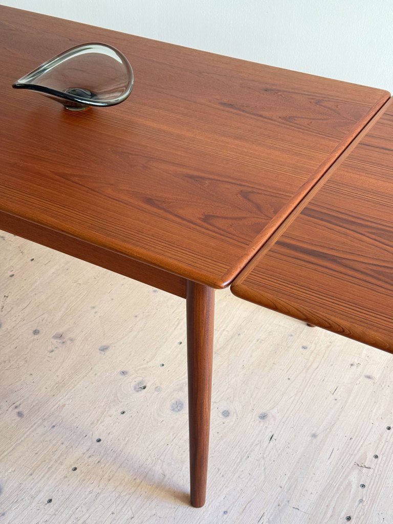 A wooden table with a smooth, rich finish and tapering legs, featuring a decorative glass object in the center.