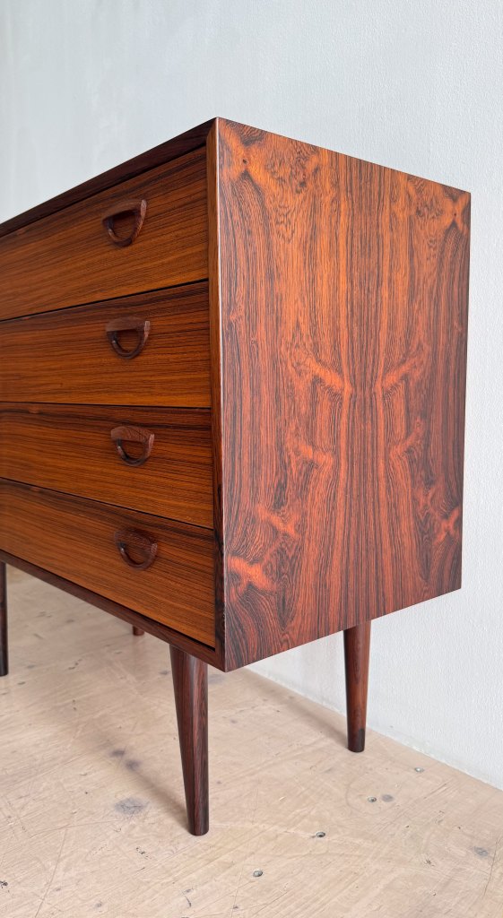 Mid-century modern wooden dresser with four drawers and tapered legs, showcasing rich wood grain.