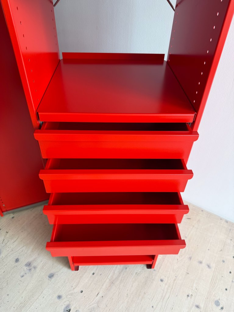 A bright red shelving unit with four drawers and a flat top shelf, placed on a wooden floor.
