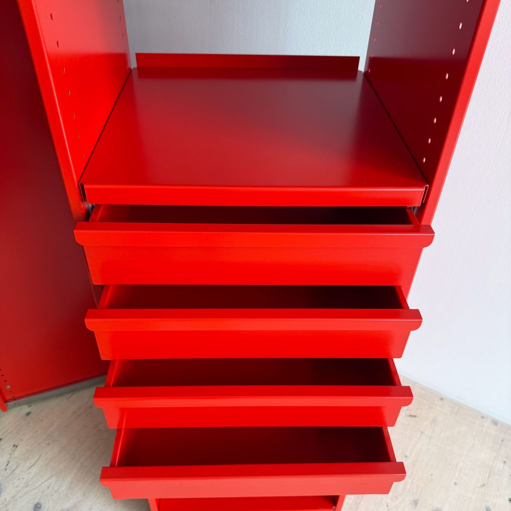 Close-up view of a vibrant red storage unit with four drawers and an open shelf, set against a light-colored background.