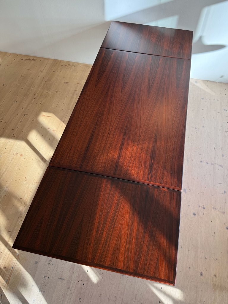 A wooden table with a rich dark brown finish, featuring a smooth surface and visible wood grain patterns.