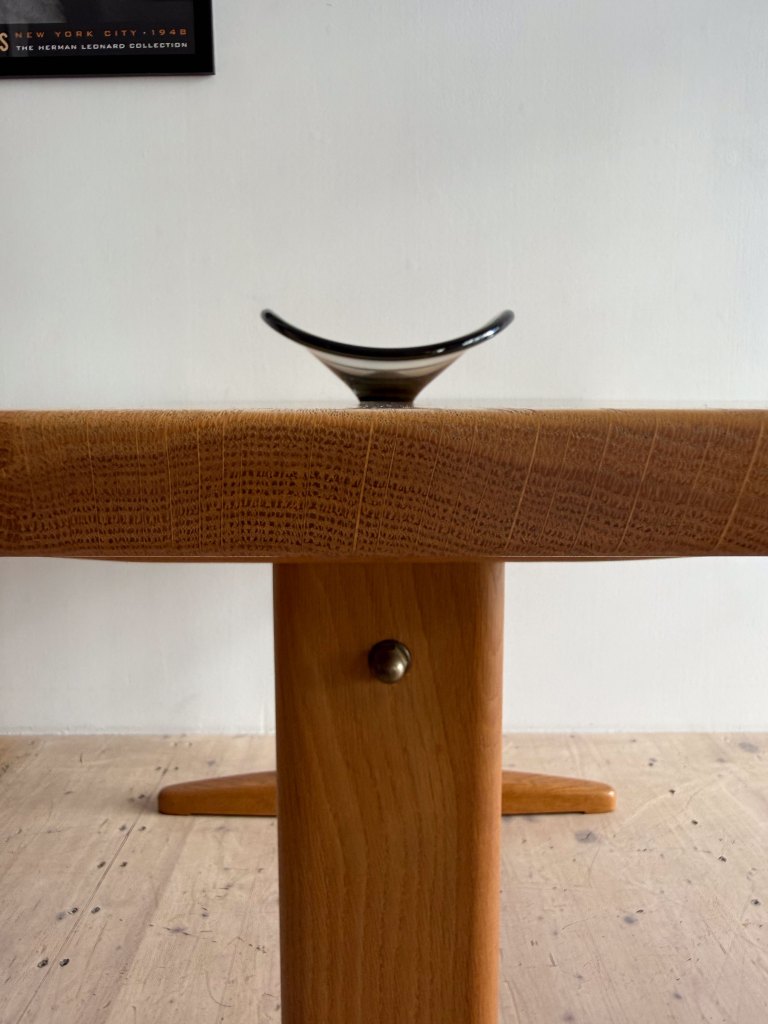 A close-up view of a wooden table featuring a textured surface and a decorative black glass bowl placed on top.